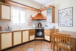 Kitchen features a central island with sink, stove, and oven, along with light cabinetry and a tiled backsplash.