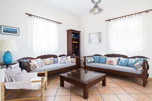 Cozy living room with two sofas, a coffee table, and a chair, perfect for relaxing and reading.