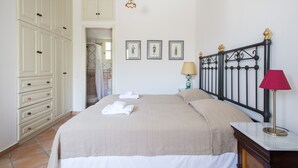 Ein ordentlich eingerichtetes Schlafzimmer mit einem Bett, einem Kleiderschrank und einem durchgehenden Türrahmen sichtbaren Badezimmer.