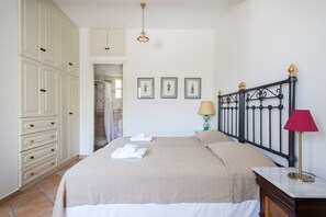 Classic hotel room with a large bed, wardrobe, and nightstand, offering a comfortable retreat.