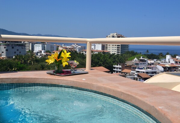 Zona de piscina con vistas a edificios y montañas al fondo.