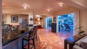 A modern kitchen with a dining area, a bedroom, and a balcony with a pool view.