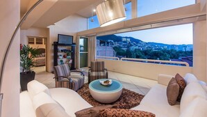 A modern living room with a large window offering a city view, a sofa set, a coffee table, and a floor lamp.