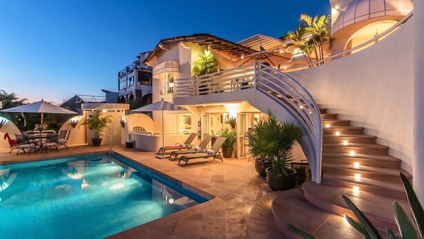 A modern villa with a swimming pool, outdoor seating, and a curved staircase.
