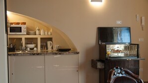Cocina compacta equipada con microondas, horno y refrigerador. Cuenta con una pequeña barra con vasos y un enfriador de vino.