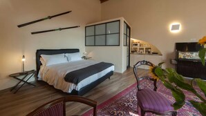 Un dormitorio con cama, mesita de noche, silla, ventana y vista a una zona de cocina.
