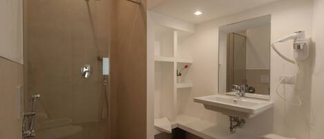 A modern bathroom with a glass-enclosed shower, a white sink, and a mirror.