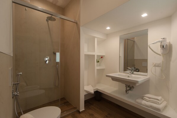 A modern bathroom with a glass-enclosed shower, a white sink, and a mirror.