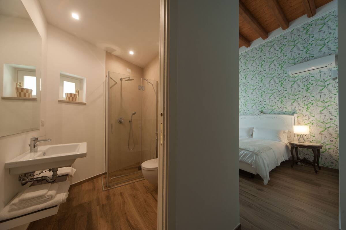 A bathroom with a sink, mirror, and shower.