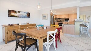 Une cuisine moderne avec des meubles en bois, un îlot central et un coin repas comprenant une table et des chaises en bois.