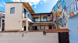 Un edificio de dos pisos con un balcón, techo de tejas y un mural colorido en la pared.