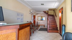 Un área de recepción con un escritorio de madera, un banco y una escalera que sube a un piso superior.