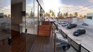 Un edificio moderno con balcón que da a un estacionamiento con varios coches.