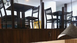 Amplia sala de estar integrada con techos altos, múltiples opciones de asiento que incluyen sofás y sillones, y una cocina a la vista.