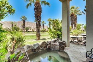 A patio area with a stone fountain, palm trees, and a view of a mountainous landscape. - Golfer's Paradise: Gem w/ Hot Tub in La Quinta (La Quinta)
