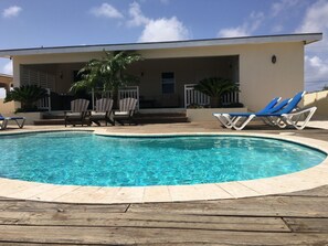 A swimming pool with lounge chairs and a covered seating area.