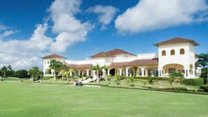 A large, multi-story building with a symmetrical facade, featuring a central courtyard with palm trees and a lawn. - Villa Fortuna Iberostar, private pool,  Bavaro beach, golf club, Wi-Fi (bavaro)