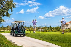 Un terrain de golf avec un chariot de golf et deux golfeurs.