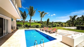 A swimming pool with two ladders, red lounge chairs, and a white outdoor sofa. - Villa Fortuna Iberostar, private pool,  Bavaro beach, golf club, Wi-Fi (bavaro)