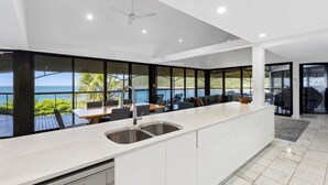 A modern kitchen with a large island, a built-in sink, and a view of the ocean. - Mermaids Reach, Stunning House on Hamilton Island (Hamilton Island)