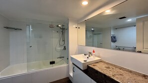 Un bagno moderno con doccia vetrata, lavabo bianco e uno specchio grande.