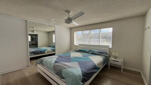 A bedroom with a bed, a nightstand, a mirror, a ceiling fan, and a window with blinds. - 1 Edmund Shores 3-BR Kings Beach Apt w/ Pool (Kings Beach)