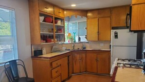 Una cucina con mobili in legno, un fornello a gas e una finestra con persiane.