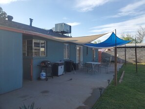 Een overdekt terras met buitenmeubilair en een barbecue.