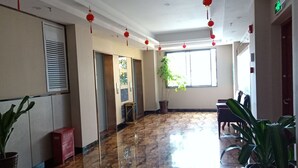 Un hall d’entrée spacieux, doté d’un sol en marbre, de décorations rouges suspendues, d’une grande fenêtre et de plantes en pot.