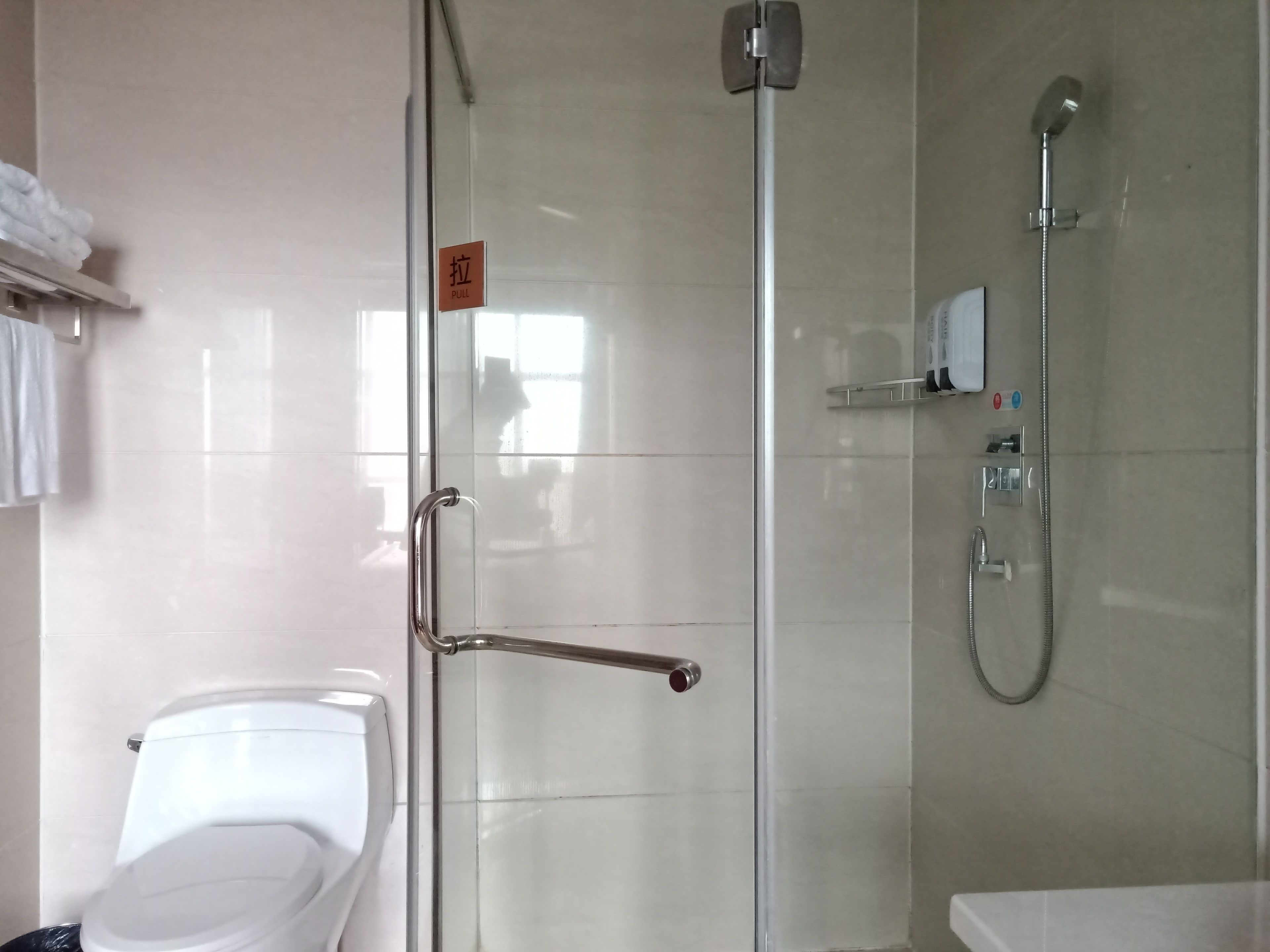 Un baño con cabina de ducha de vidrio, inodoro y lavamanos.