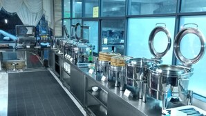 Un buffet disposant de présentoirs en acier inoxydable, d’un sol carrelé et de grandes fenêtres.