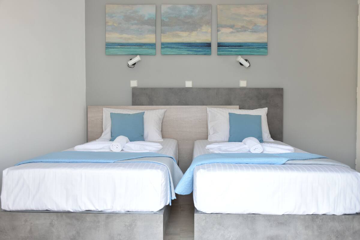 A double bed with a grey headboard, two bedside tables, and a wall-mounted night light.