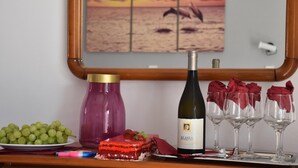 Ein Tisch mit einer Flasche Alasia-Wein, einer Platte mit Trauben, einem Dessert und vier Weingläsern mit roten Servietten.