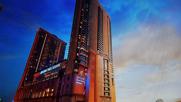 Een hoog gebouw met een opvallend bord van Times Square, omringd door andere wolkenkrabbers.
