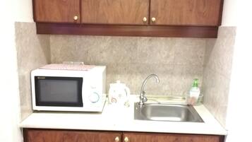 A compact kitchen with a microwave, sink, and cabinets.