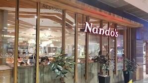 Een restaurant genaamd 'Nandos' met een modern interieur, zichtbare zitplaatsen en potplanten.