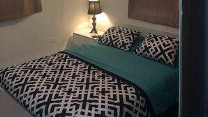A bedroom with a bed, a nightstand with a lamp, and a ceiling fan.