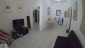 A living room with a sofa, TV, and a dining area with a table and chairs.
