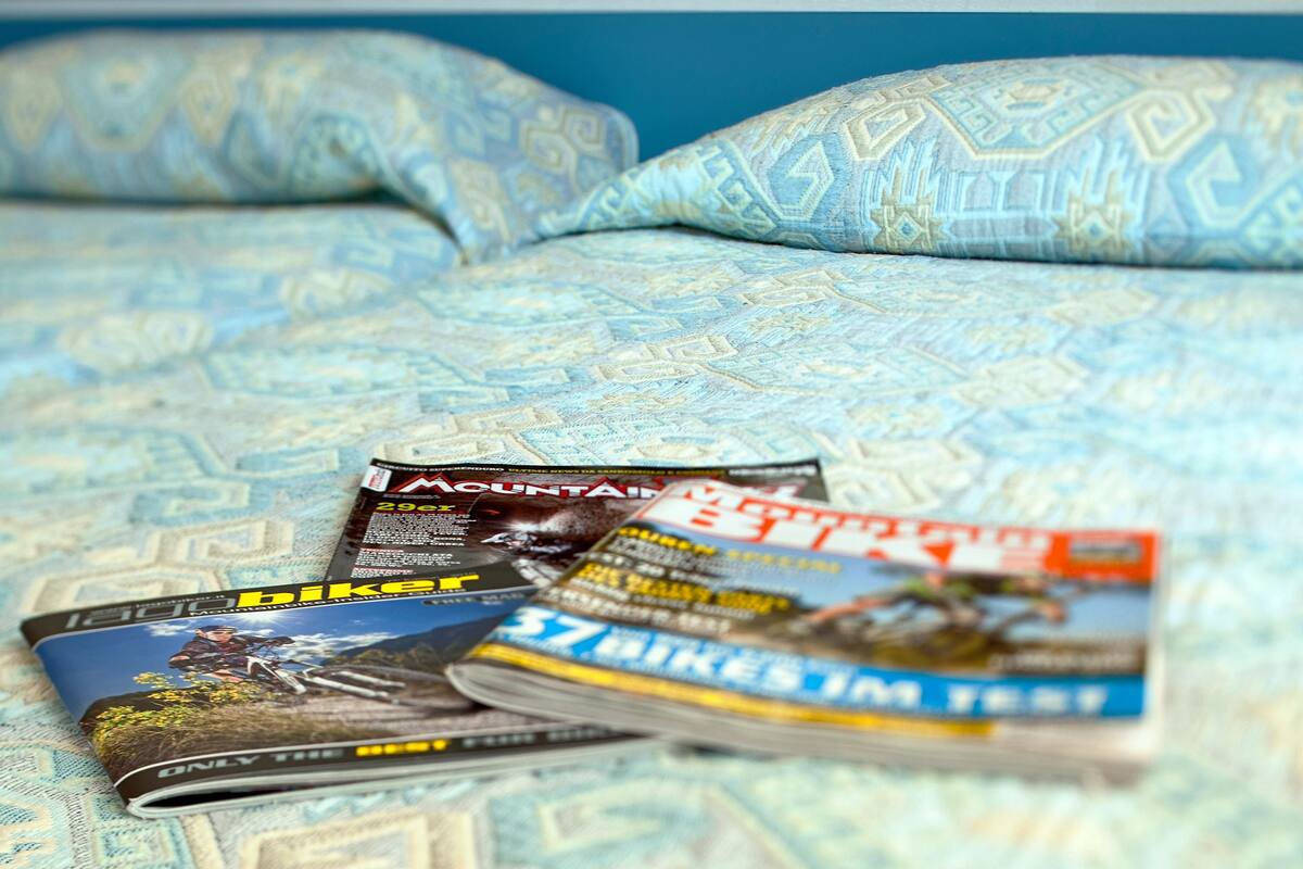 A bed with patterned bedding and several magazines on it.