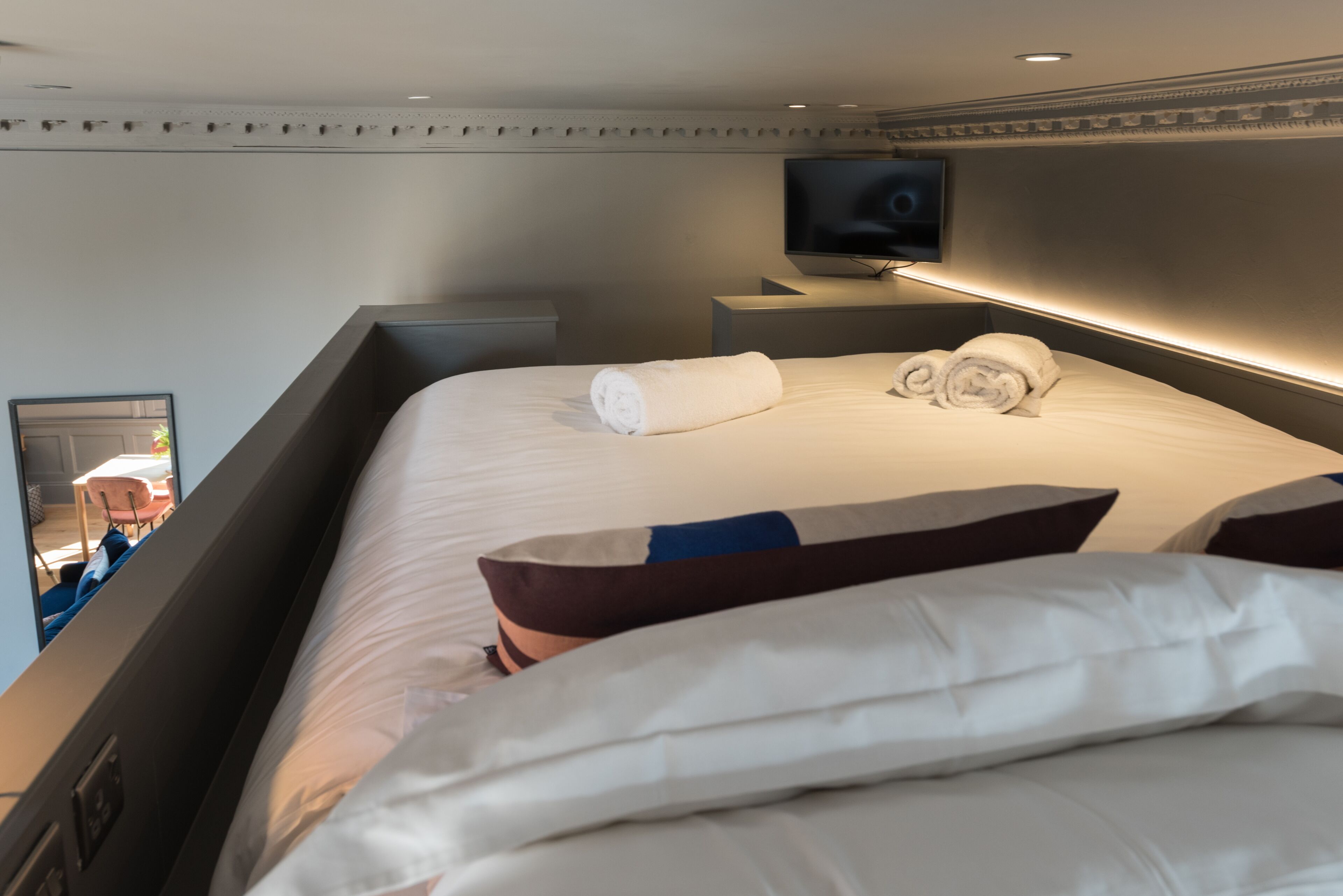 A hotel room with a bed, a television, and a mirror.