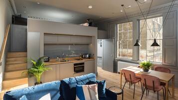 Un interior moderno con cocina, comedor y un sofá azul.