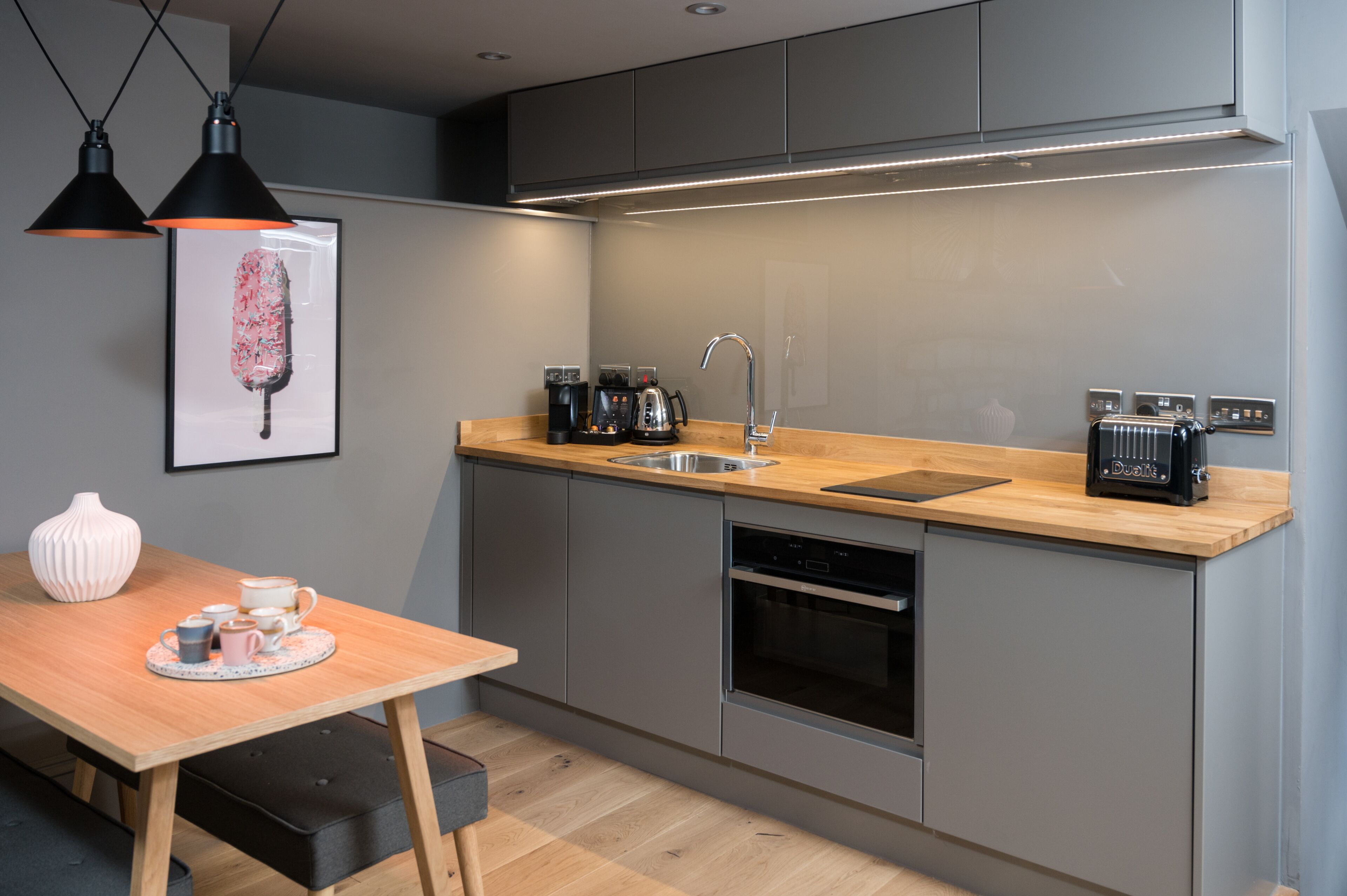 Een moderne keuken met een houten aanrecht, roestvrijstalen apparatuur, een spoelbak en hanglampen.