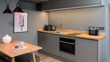 Een moderne keuken met een houten aanrecht, roestvrijstalen apparatuur, een spoelbak en hanglampen.
