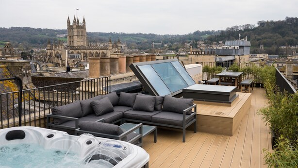 Une terrasse sur le toit avec un jacuzzi, un espace salon et une vue sur un bâtiment historique.