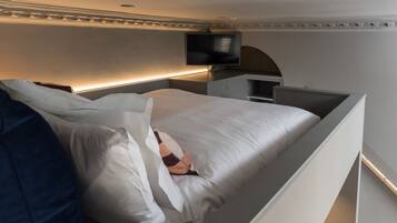 Een moderne slaapkamer met een bed, een flatscreen televisie aan de muur en een nachtkastje.
