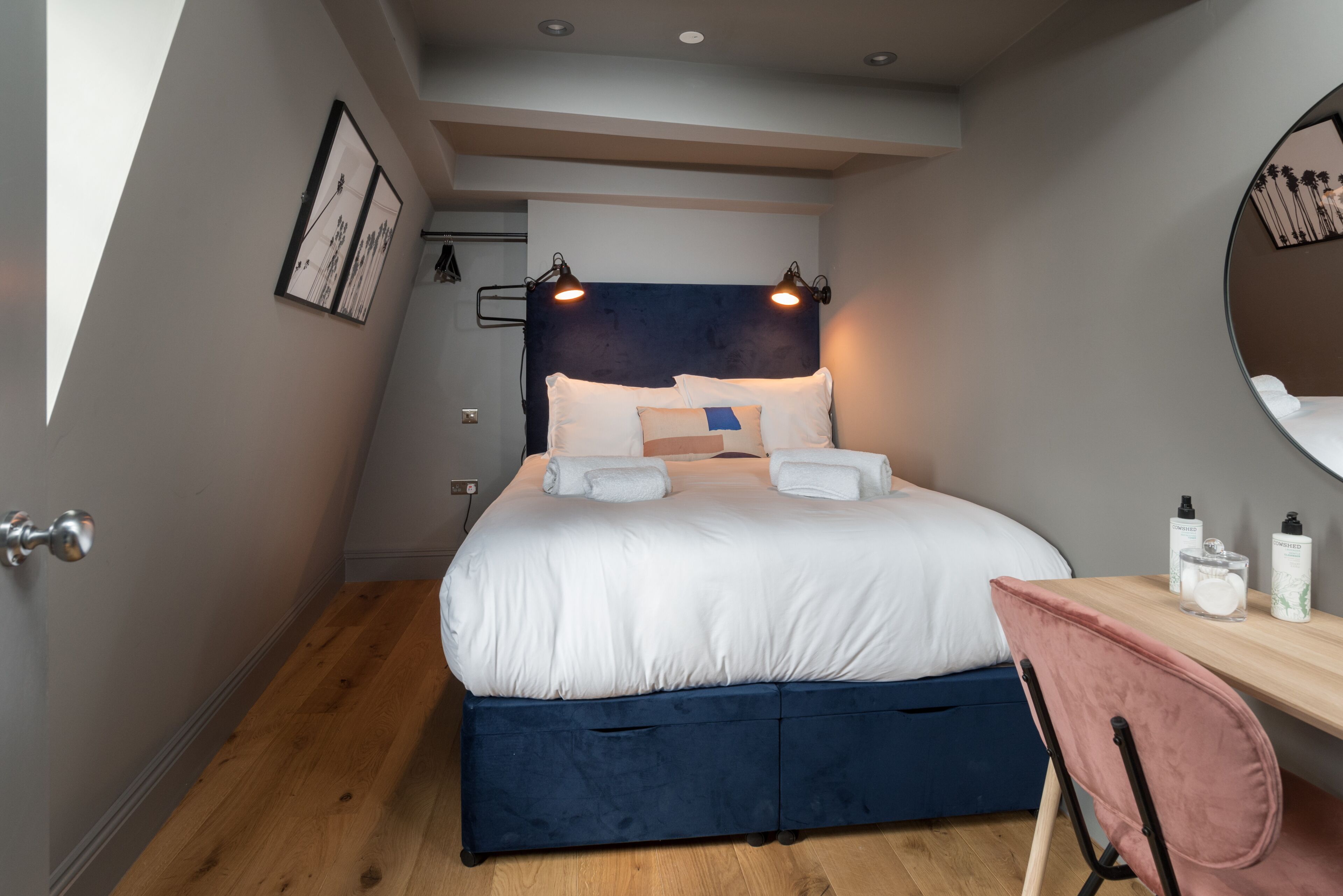 Un dormitorio con cama, lámparas de noche, escritorio y espejo.