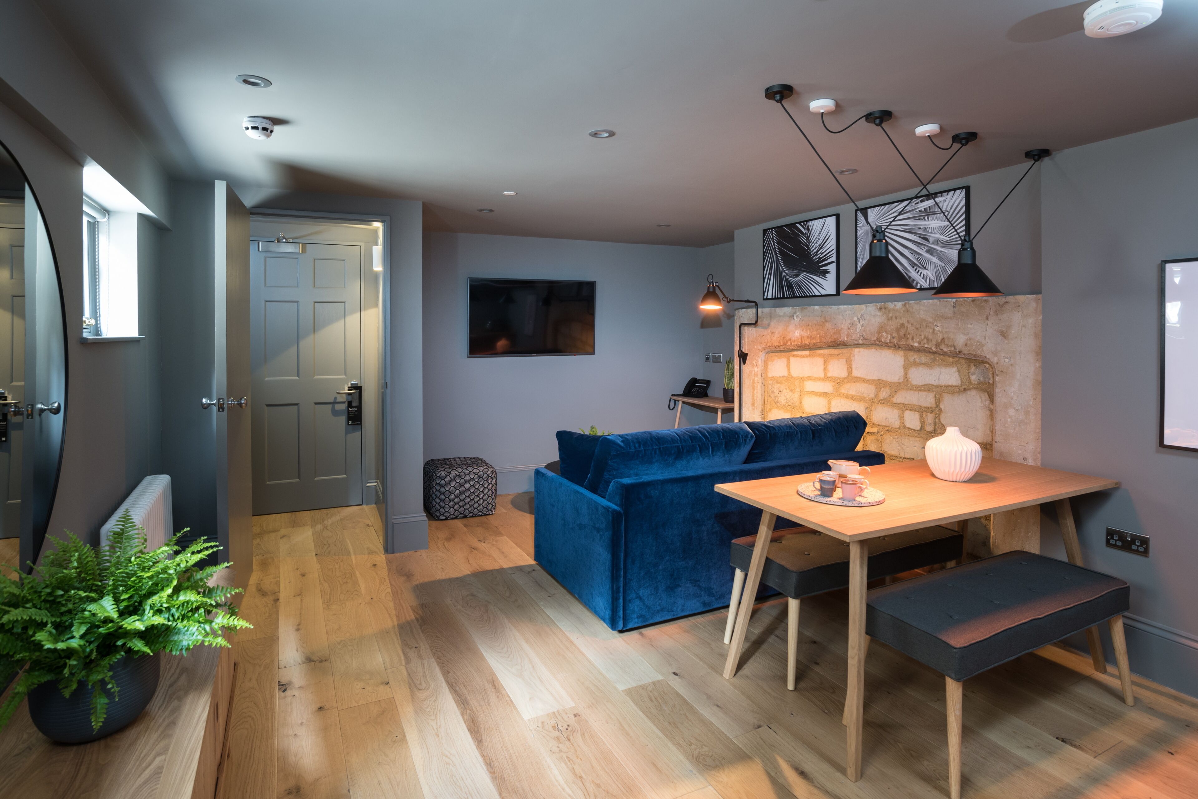 Een moderne keuken met een blauwe bank, een houten tafel en hanglampen.
