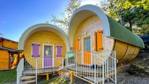 Twee houten vakantiehuisjes met gebogen daken en een klein terras.