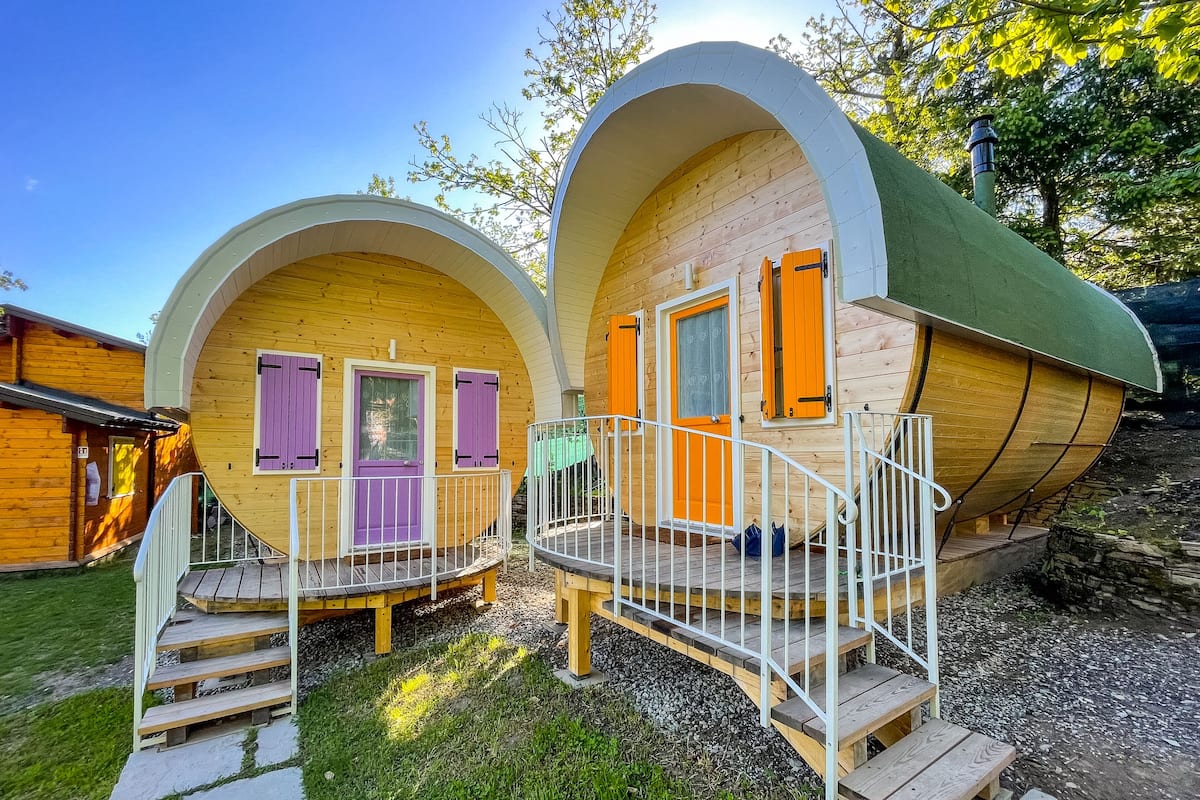 Dos cabañas de madera con techos arqueados y un pequeño porche.