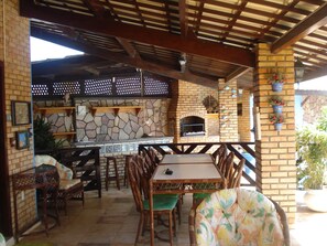 An outdoor patio with a stone fireplace, wooden furniture, and potted plants.